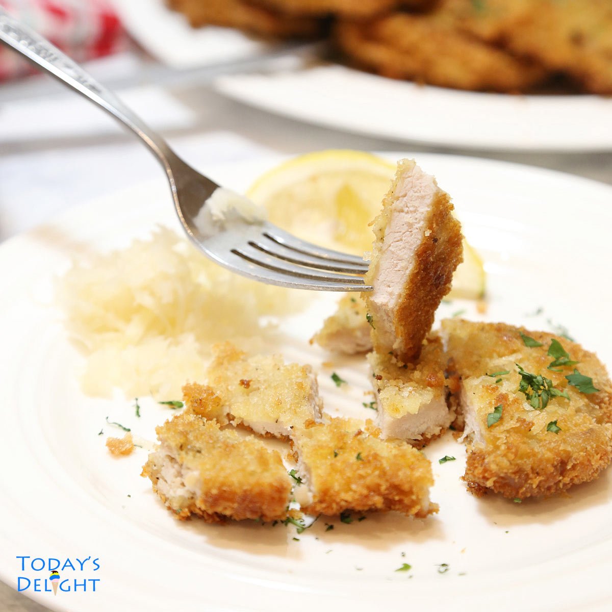 Plate of fried pork loin on plate with a slice in a fork.