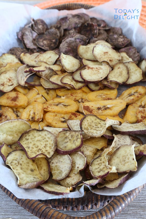 Pumpkin spice baked sweet potatoes and banana chips on a wooden tray lined with parchment paper.