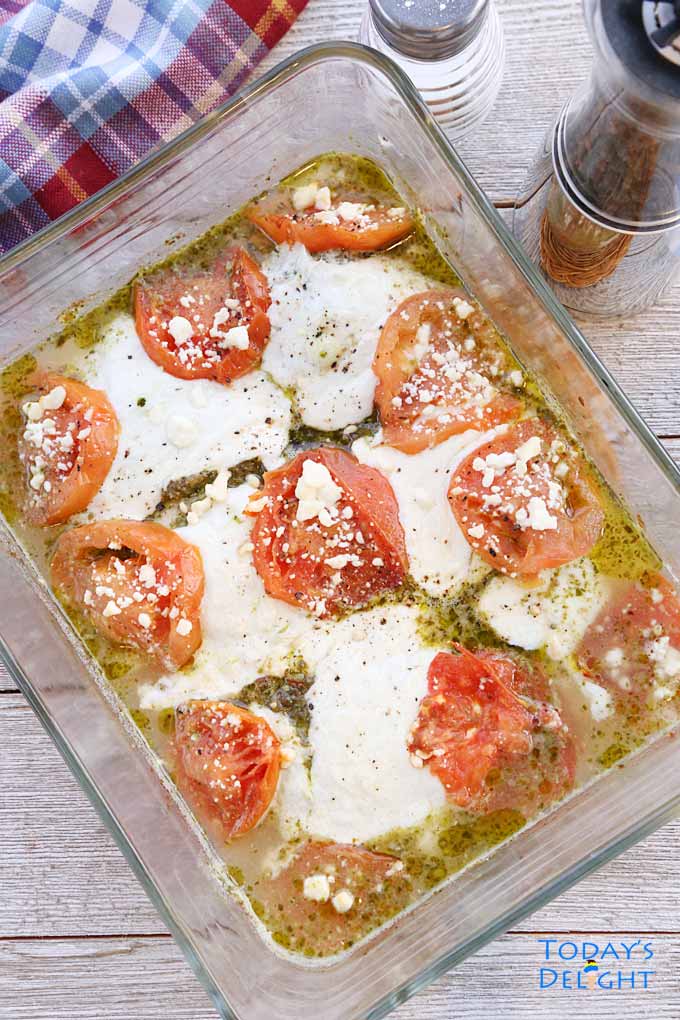 Baked Chicken Pesto with Tomato Mozzarella and Feta Cheese in a pyrex pan.