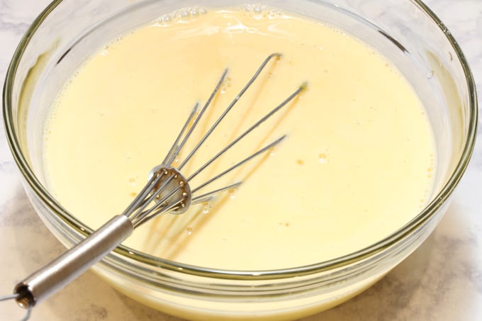 Combined egg yolks, milk, condensed milk, lime extract in a bowl with a whisk.