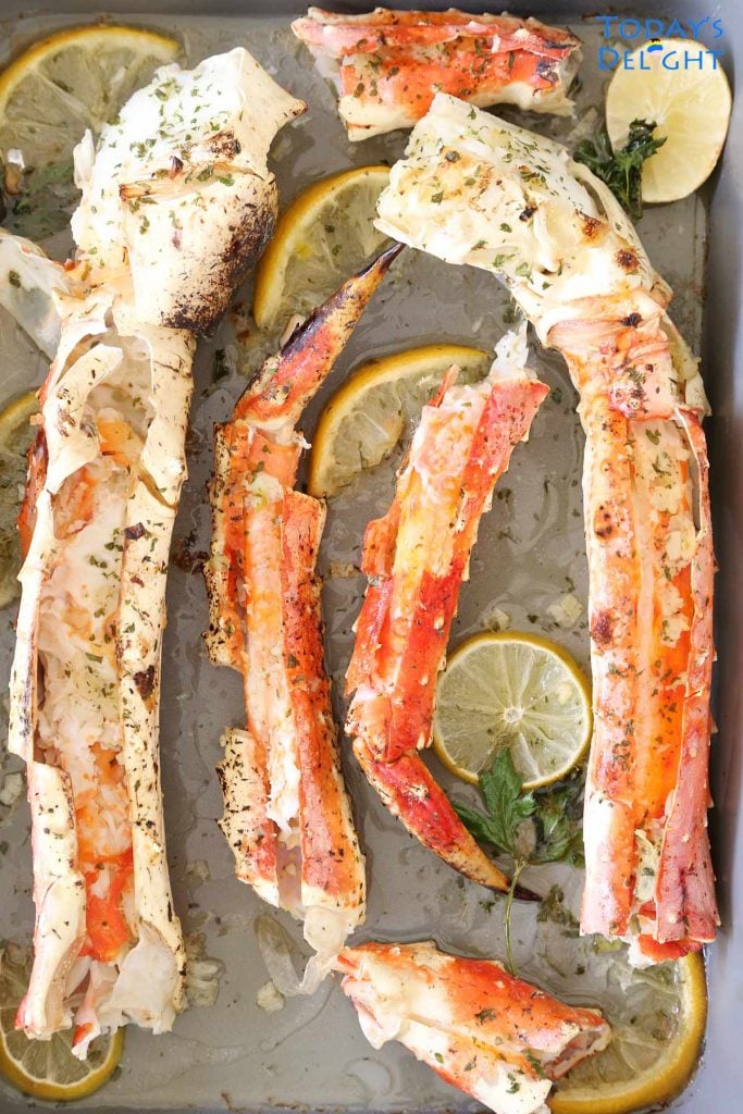 King crab legs in lemon garlic butter sauce and lemon wedges.
