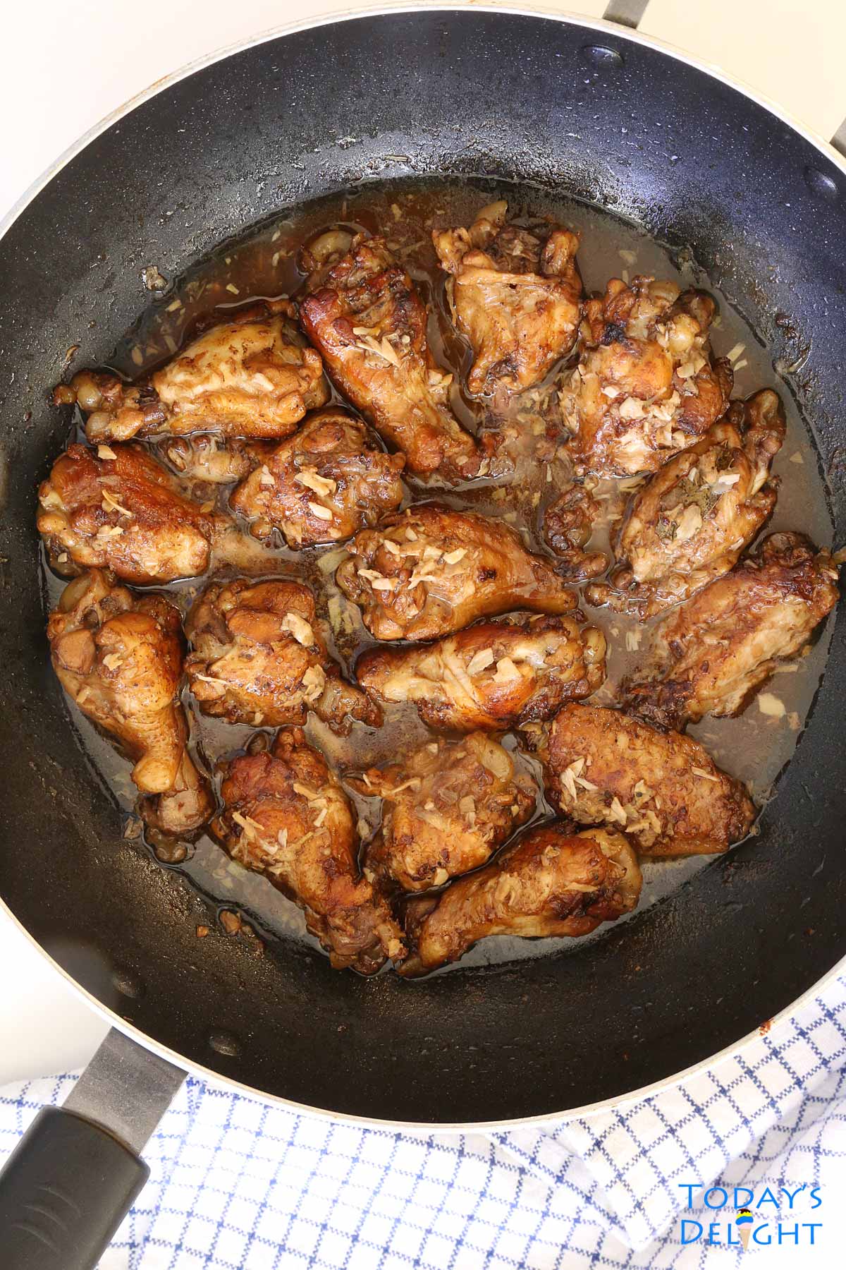Filipino Chicken Adobo in a skillet is stewed chicken wing in vinegar garlic mixture.