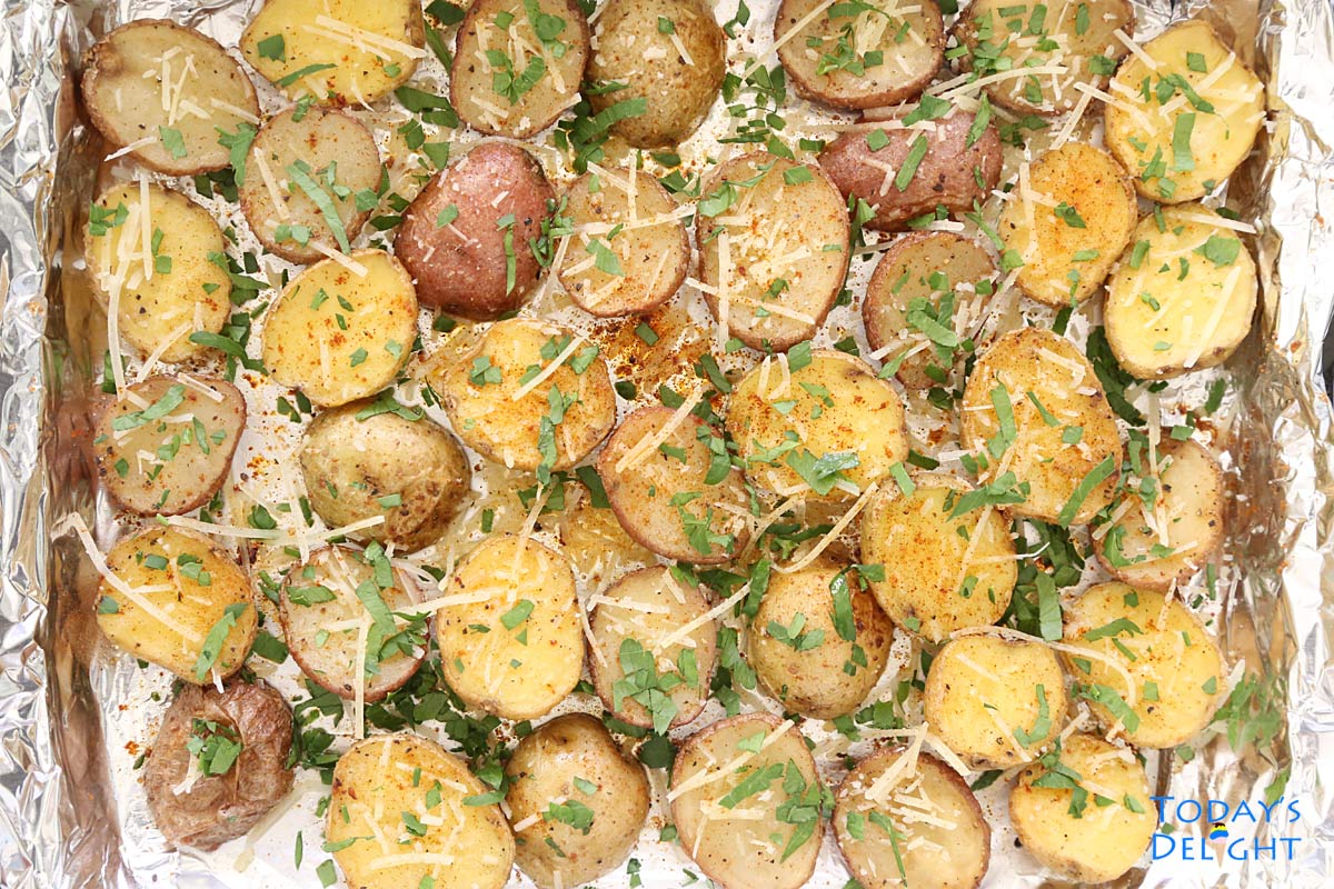 Oven Roasted Baby Potatoes garnished with cheese and parsley in baking sheet lined with foil.