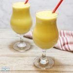 2 mango smoothie drink in hurricane glass with red straws.