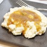 Mashed potatoes with brown gravy on a plate.