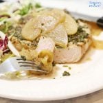 Sliced pork chop topped with cooked apple and salad on the side.