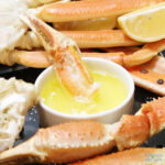 A platter of snow crab legs with lemon and claw dipped in melted butter.and