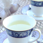 Two cups of hot ginger drink and a tea pot.