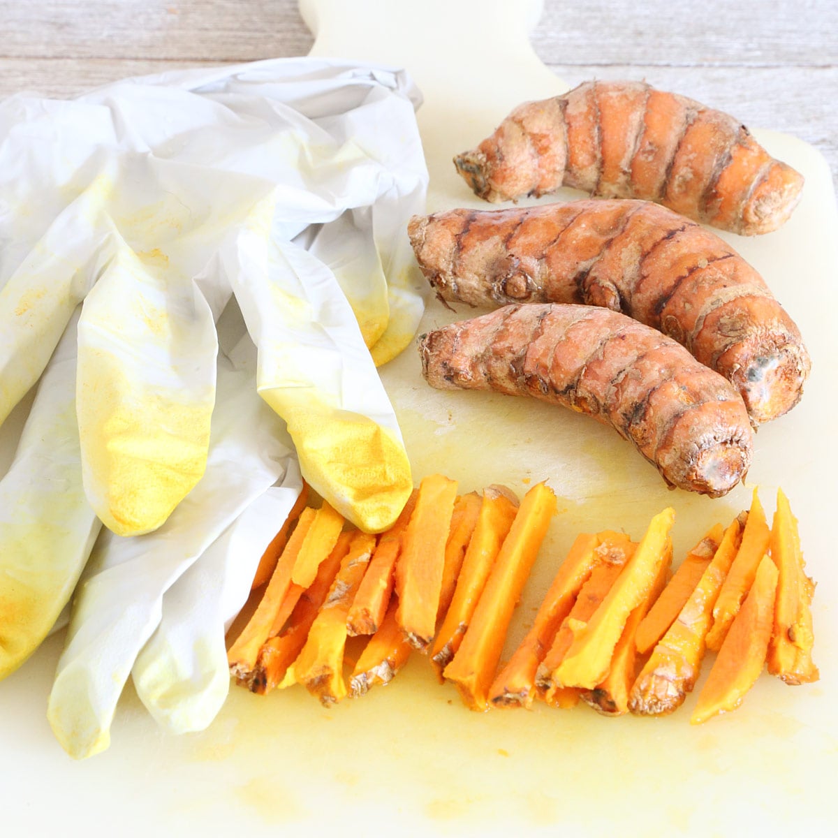 Three unpeeled turmerics and one peeled then sliced to matchstick sizes wearing gloves.