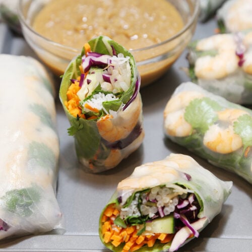 Pieces of Vietnamese fresh vegetables spring rolls with shrimp on a platter with peanut sauce.