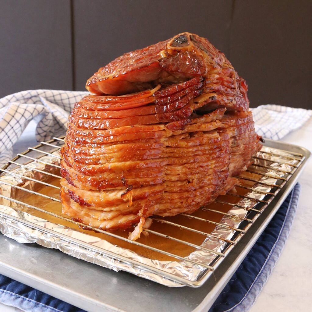 Baked honey glazed ham on a shallow pan with rack.